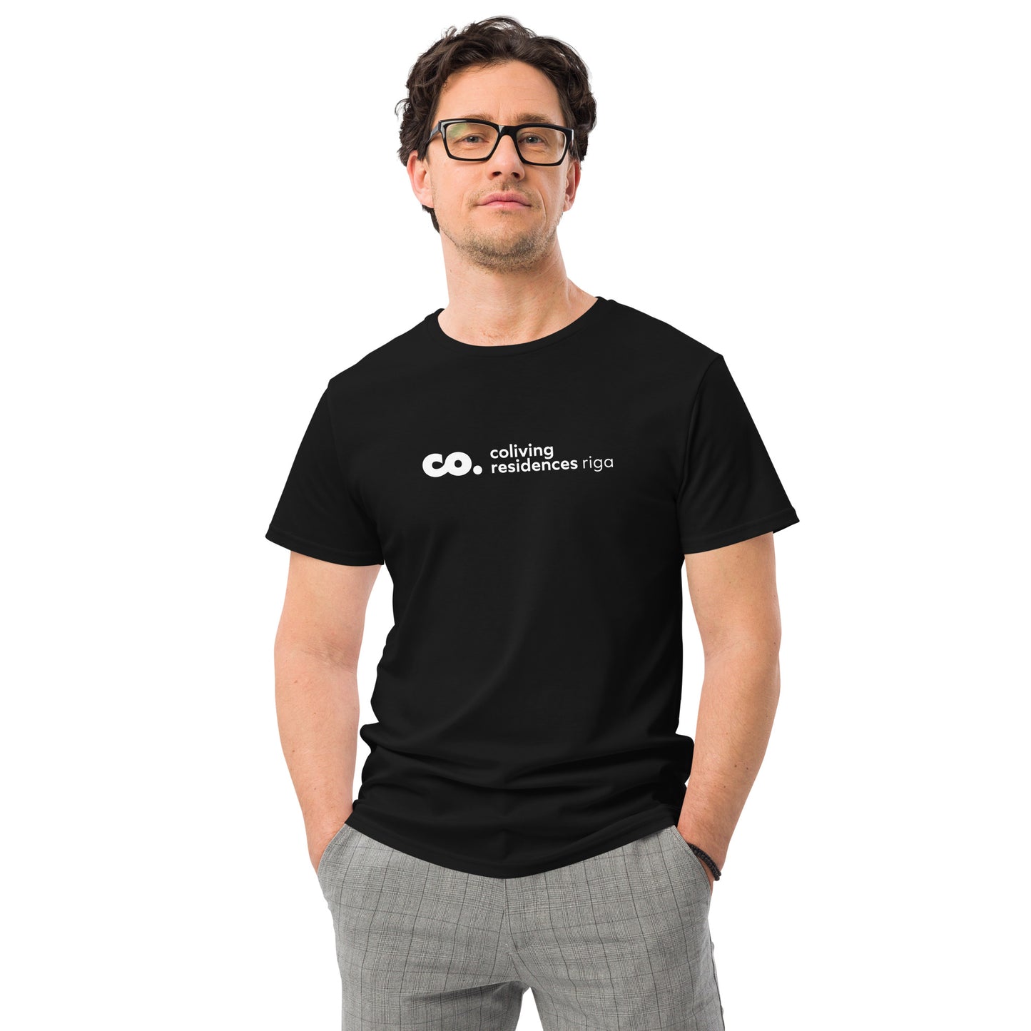 Front view of a white man wearing a black t-shirt with logo of coliving residences riga