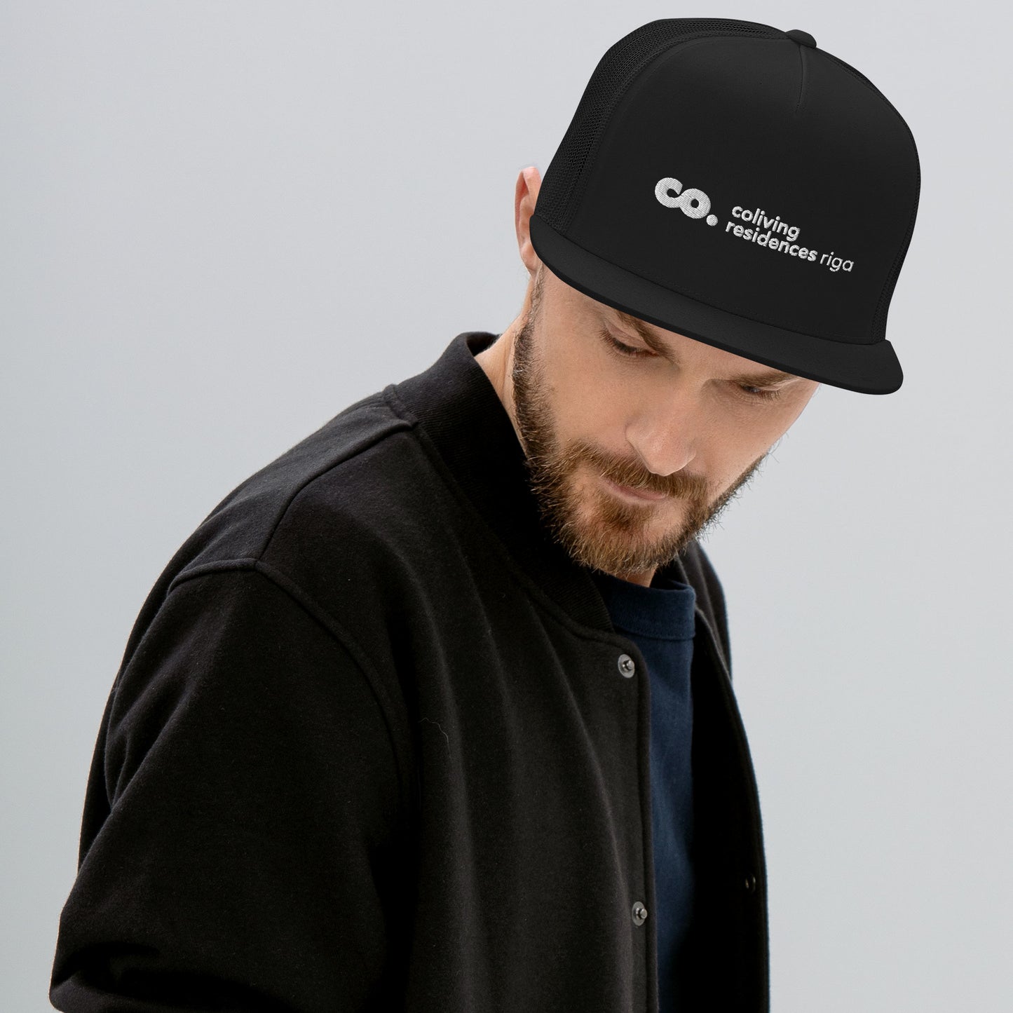 White man with a beard wearing a black trucker cap featuring the Coliving Residences logo