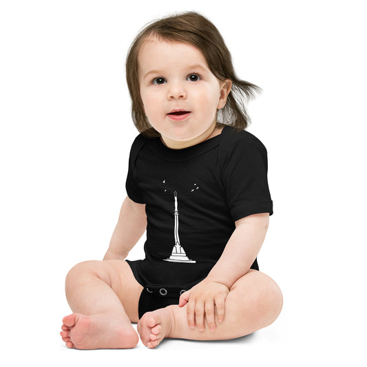 Front of baby wearing a black one piece featuring Riga's Freedom momument