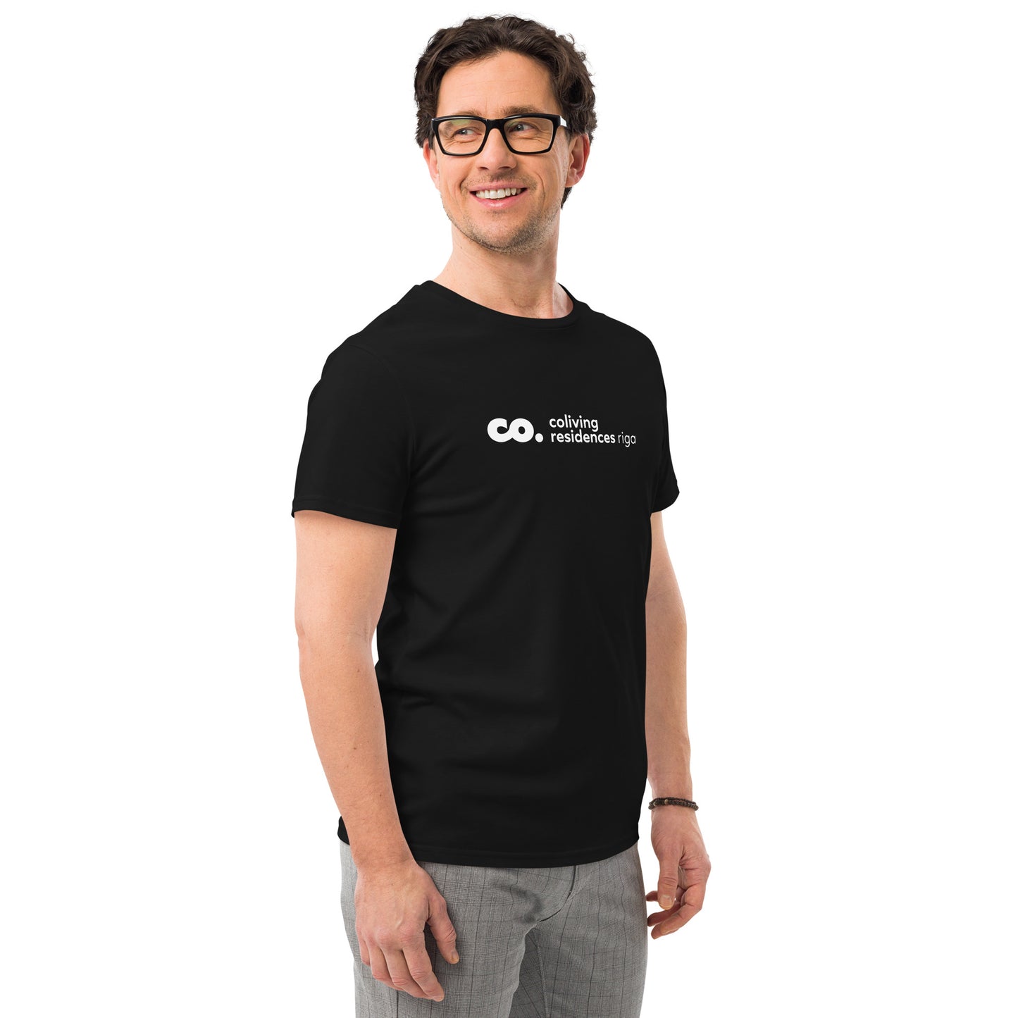 Front view of a white man wearing a black t-shirt with logo of coliving residences riga