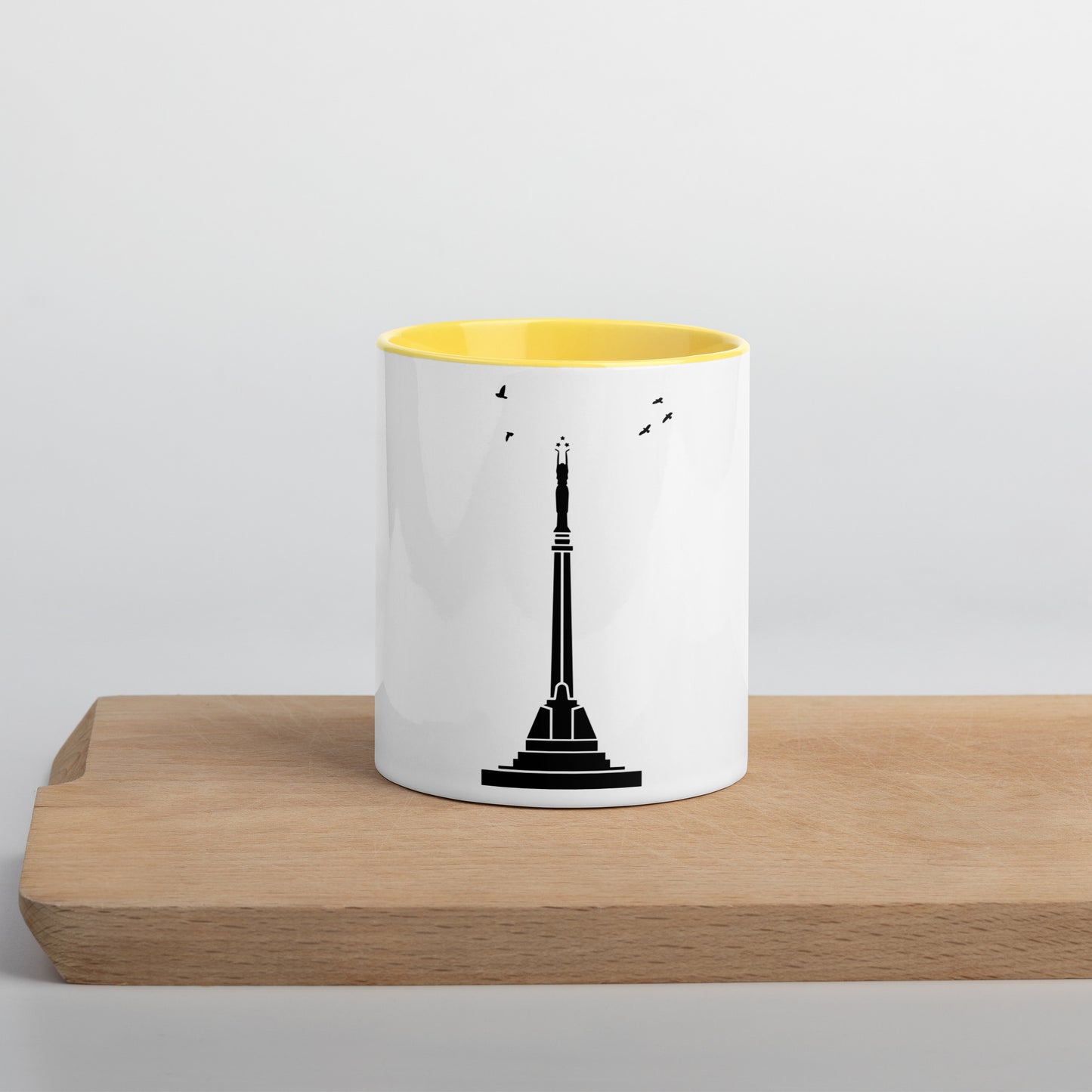 white coffee mug with yellow inside featuring Riga's Liberty Monument